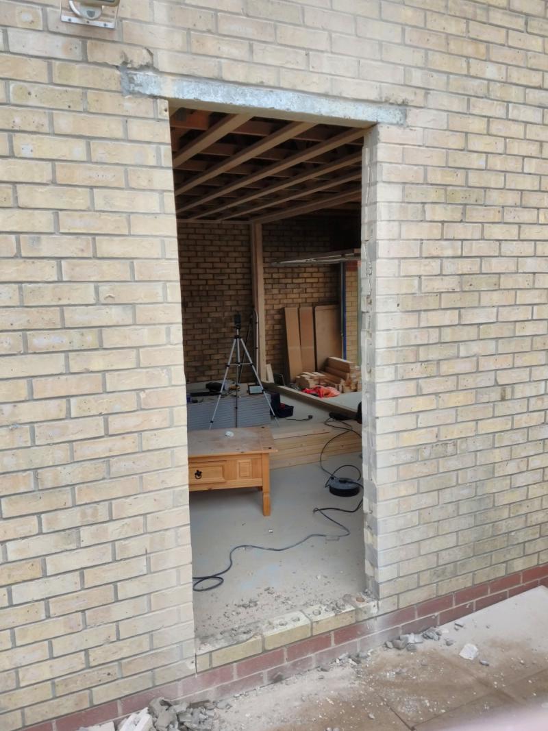 A view of the same wall, but now the bricks underneath the lintel are removed down to one row above the differently coloured bricks, providing a view into the garage.