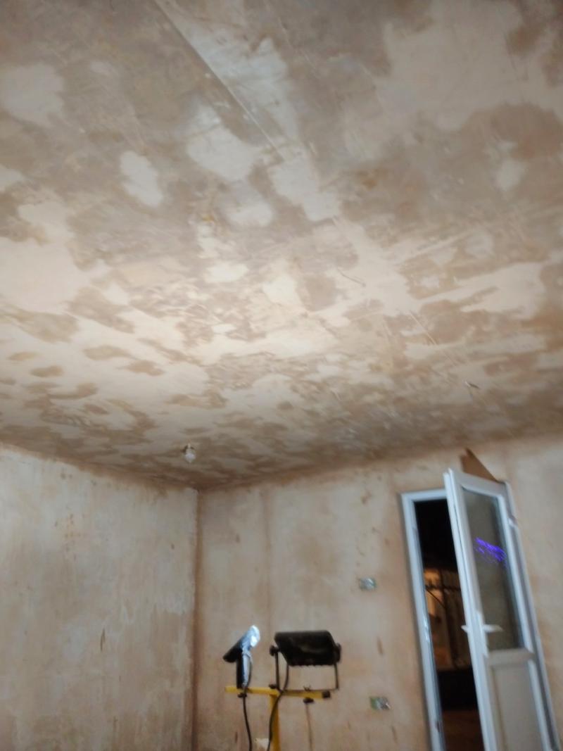 View toward the ceiling which has been plastered. Like the walls, it is a mocha-brown colour, but it's very patchy and uneven looking.
