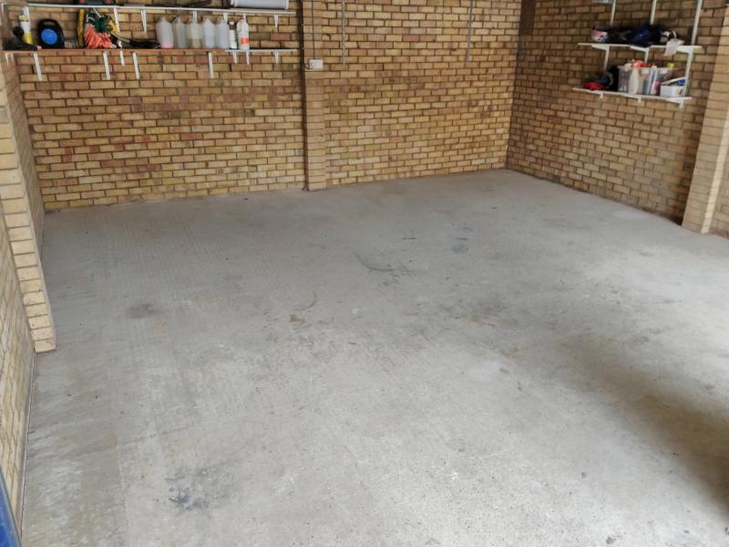 View of the garage, showing a completely empty concrete floor. The walls still have shelves.