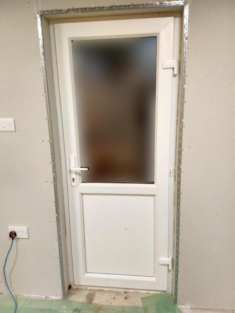 View of the door seen from inside. On the plasterboard surrounding, the external corners left, right, and top are covered with a strip of metal corner bead