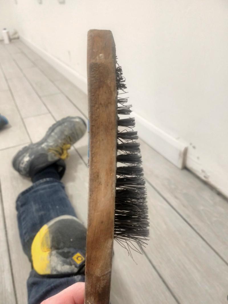 Close-up of a wooden wire brush with the steel strands going from about an inch (2.54cm) long by the bottom to a few millimetres long by the top, demonstrating how worn down it got
