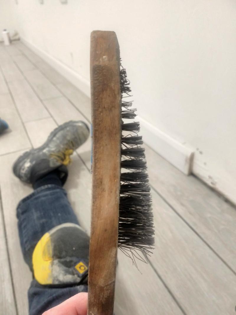 Close-up of a wooden wire brush with the steel strands going from about an inch (2.54cm) long by the bottom to a few millimetres long by the top, demonstrating how worn down it got