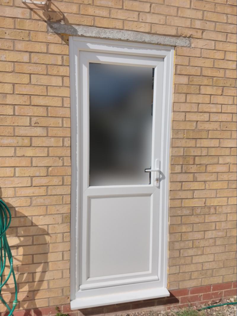 Photo of the door, closed, now with expanding foam cut back and the gap covered with a white plastic trim all around.