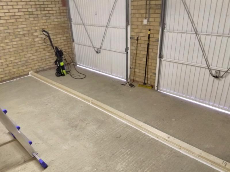Lengths of lumber are mounted to the concrete floor, about 1.4 metres away from the garage gates. Along the inner edges, white caulk seals the gap between floor and wood