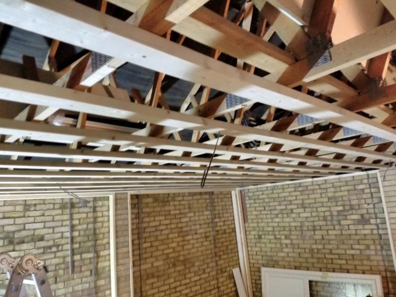Close-ish view of the ceiling beams; in a few places, cable can be seen protruding through a hole in the beams