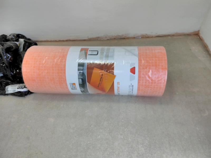 An orange roll in plastic wrap; the Schlüter DITRA floor decoupling membrane.