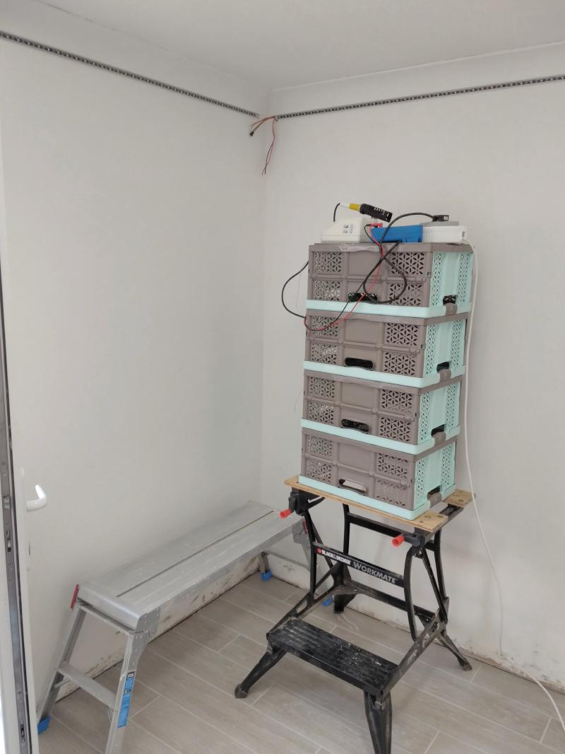 Setup for soldering near the ceiling: In the very corner is a small work platform to stand on. Next to it is a sawhorse acting as a table. On top of that is a stack of 4 upside down plastic folding boxes which gets a work surface less than about a metre away from the ceiling. On top of that is a soldering station, a multi-socket/extension lead, and a multimeter.