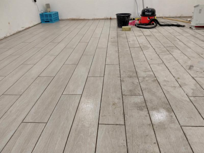 View of tiled floor, half clean, half covered in mortar residue (patchy grey)