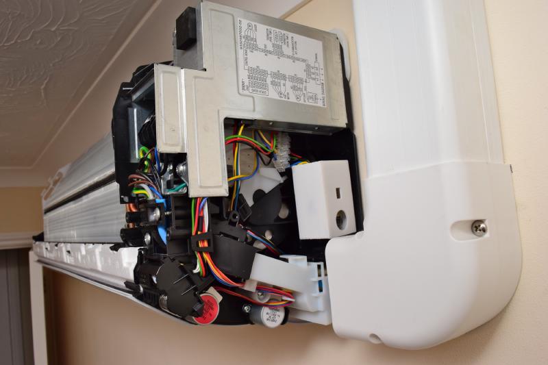A look from the right side into the opened up A/C unit. The white 3D printed box sits in an open area under a large metal box containing more control circuitry. Nearby are the screw terminals, with new wires leading to the infrared sensor module connected.