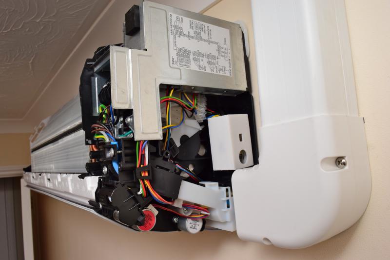 A look from the right side into the opened up A/C unit. The white 3D printed box sits in an open area under a large metal box containing more control circuitry. Nearby are the screw terminals, with new wires leading to the infrared sensor module connected.