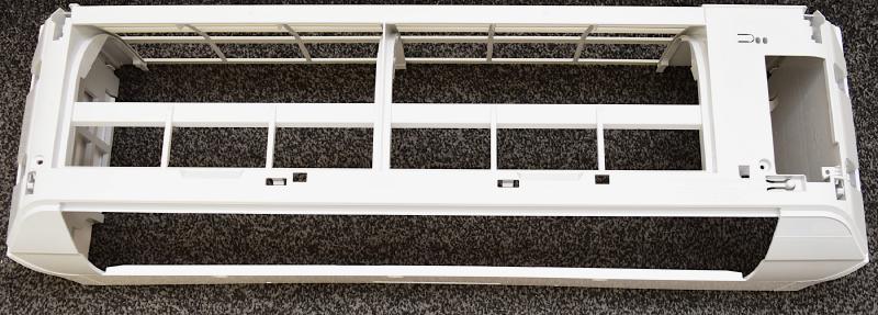 The removed A/C unit shell set on the floor. It's white plastic that reaches all the way to the wall