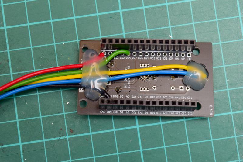 The previous IR Controller for ESPHome circuit board now seen on the other side. The wires are soldered on as described and all lead over to the left edge into a neat bundle. There's a blob of hot glue where the yellow and blue wires attach to the LED's pads on the right side of the board, and a bigger blob covering all 5 wires on the left edge of the board.