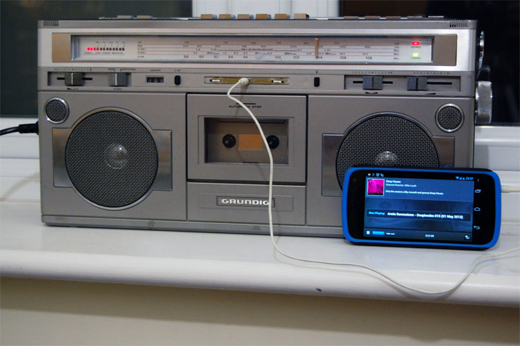 Photo of the front of the radio, with audio cable plugged into the new line-in socket. A smartphone playing music is leaning against the radio as an example audio source
